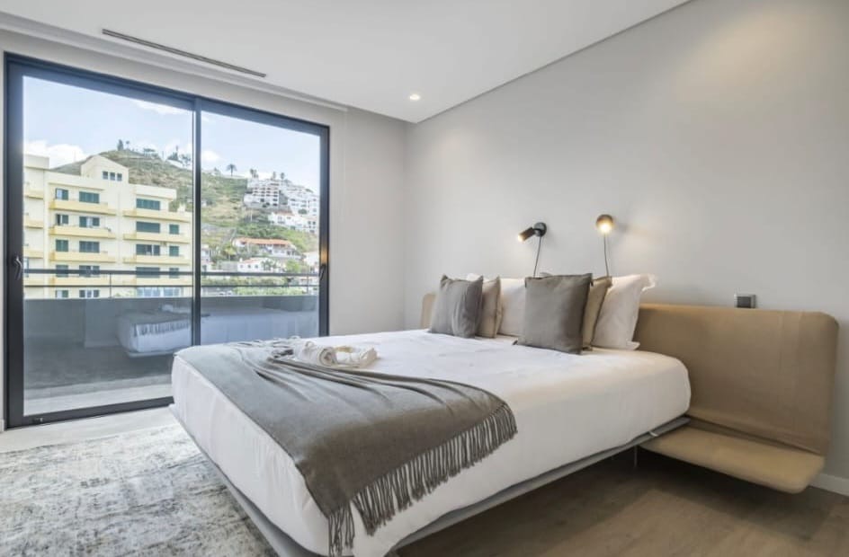 Doppelschlafzimmer mit gepolstertem Kopfteil und verglaster Tür zum Balkon, Penthouse in São Martinho, Funchal