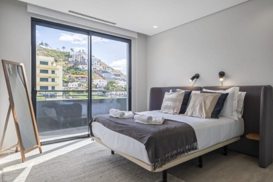 Schlafzimmer mit verglaster Schiebetür zum Balkon und Standspiegel, Penthouse in São Martinho, Funchal