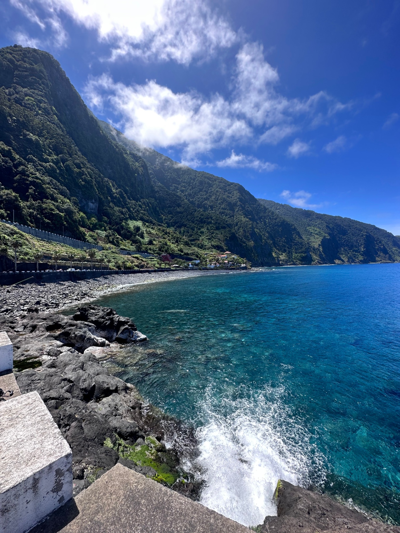 Turquoise Atlantic coast beneath steep green cliffs on Madeira