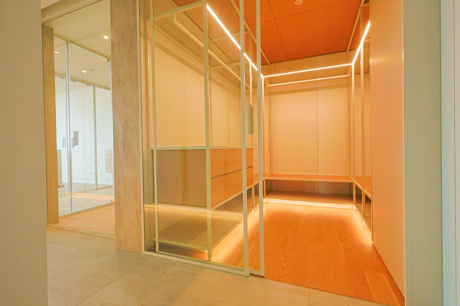 Walk-in closet of the master suite with backlit shelving and glass doors, T3 apartment, Funchal